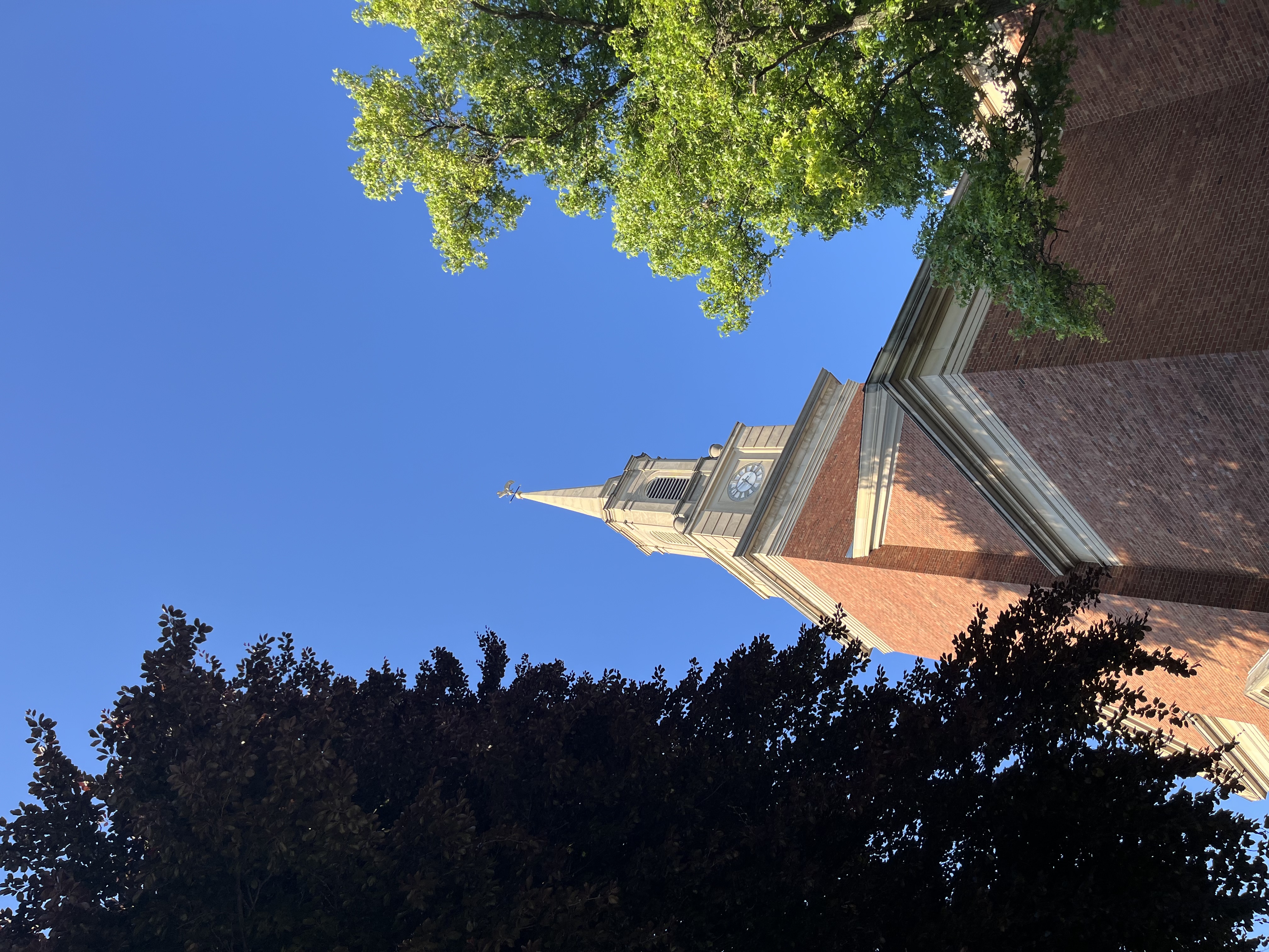 Hicks Memorial Chapel on the Pittsburgh Theological Seminary campus in the evening. The chapel appears firebrick red and on the left and right there are big, green, leafy trees.